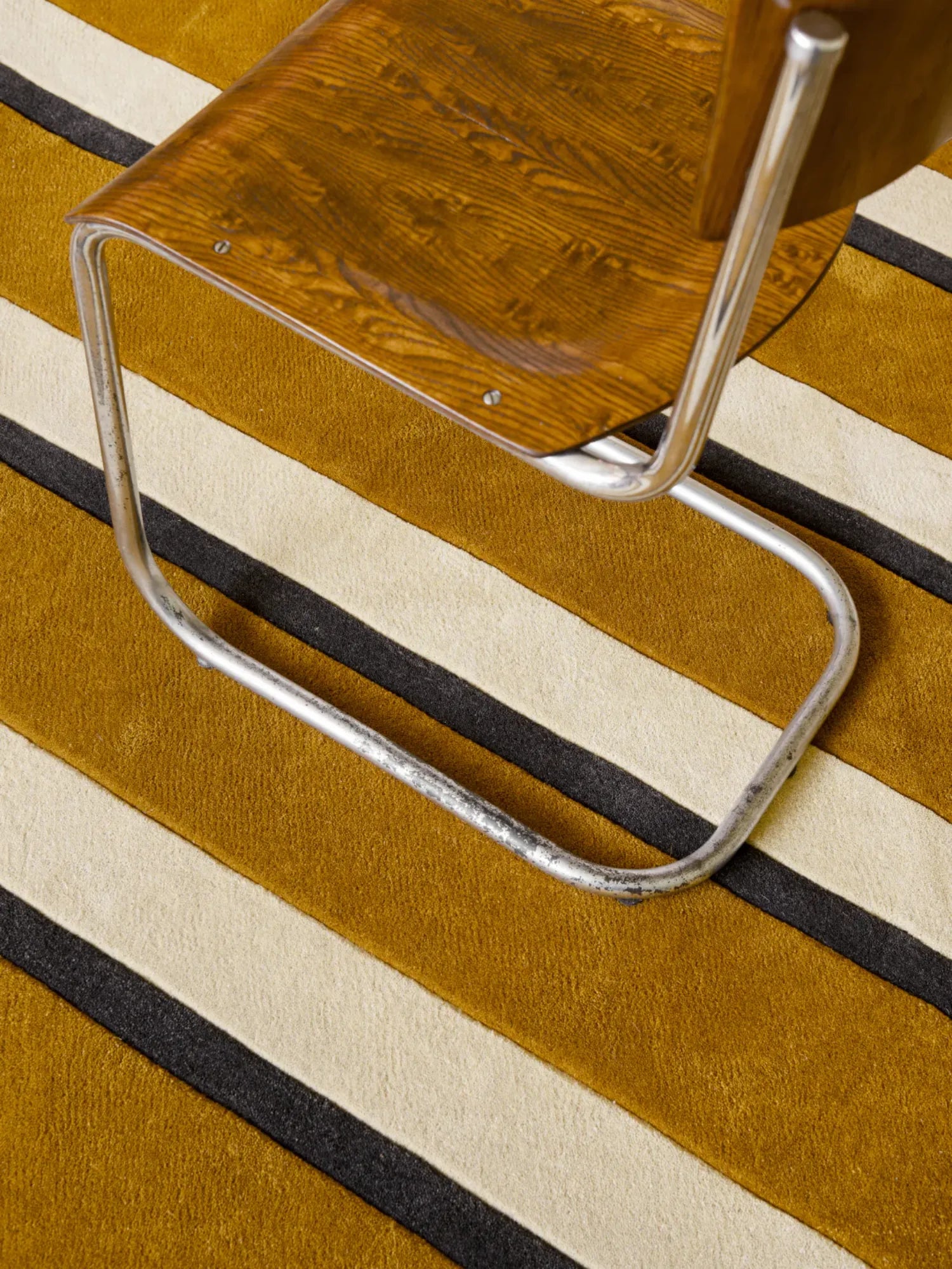 Layered Diagonal Wool Rug, a luxurious striped area rug in mustard yellow, off-white, and dark gray, made from soft wool fibers. Perfect for adding modern warmth and style to any living room or bed...
