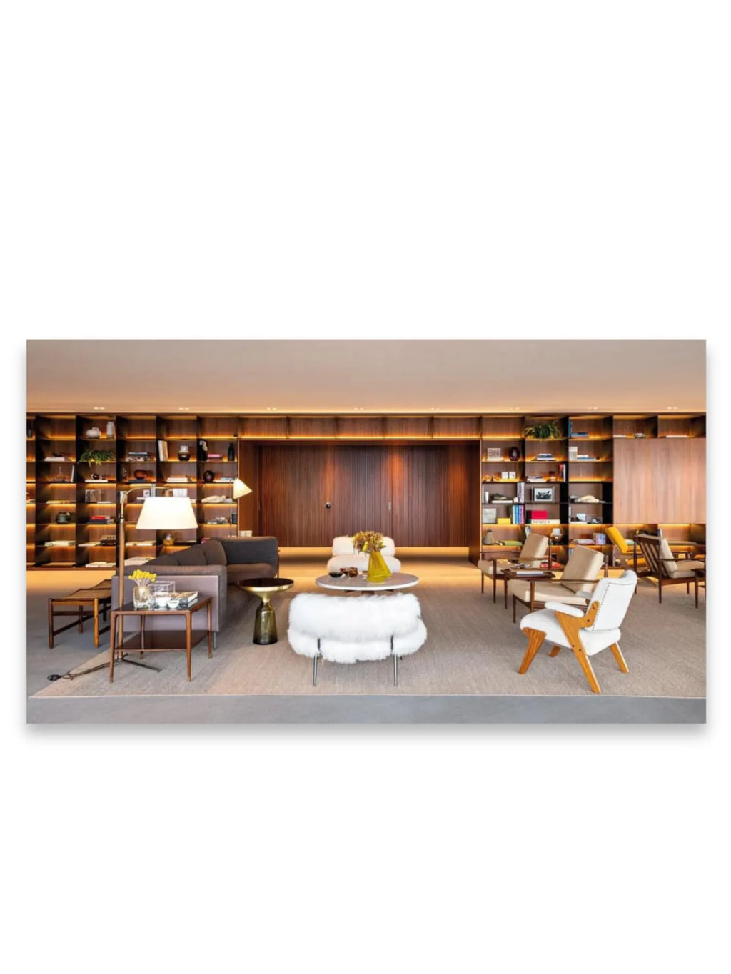Book World’s Finest Apartments, featuring a sophisticated living room with built-in dark wood shelving illuminated by warm LED lighting, a plush gray sofa, white furry ottoman, and several elegant modern chairs. This inspirational book is perfect for interior design enthusiasts and luxury real estate professionals seeking premium apartment ideas.