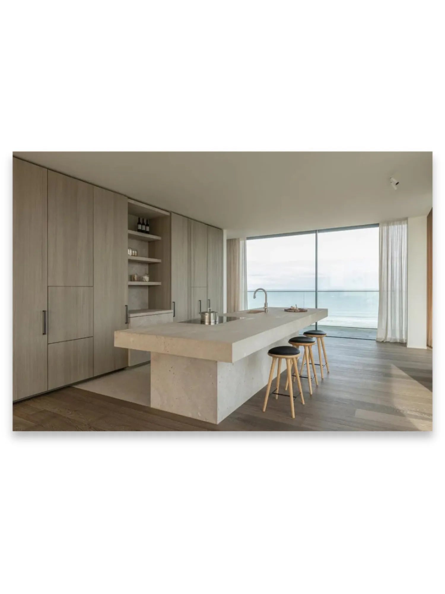 Book World’s Finest Apartments, featuring a stunning modern kitchen with light wood cabinetry, a large concrete island with three wooden stools, and dark engineered wood flooring. This architecture book offers inspiration for luxury design enthusiasts and those seeking sophisticated apartment living ideas.