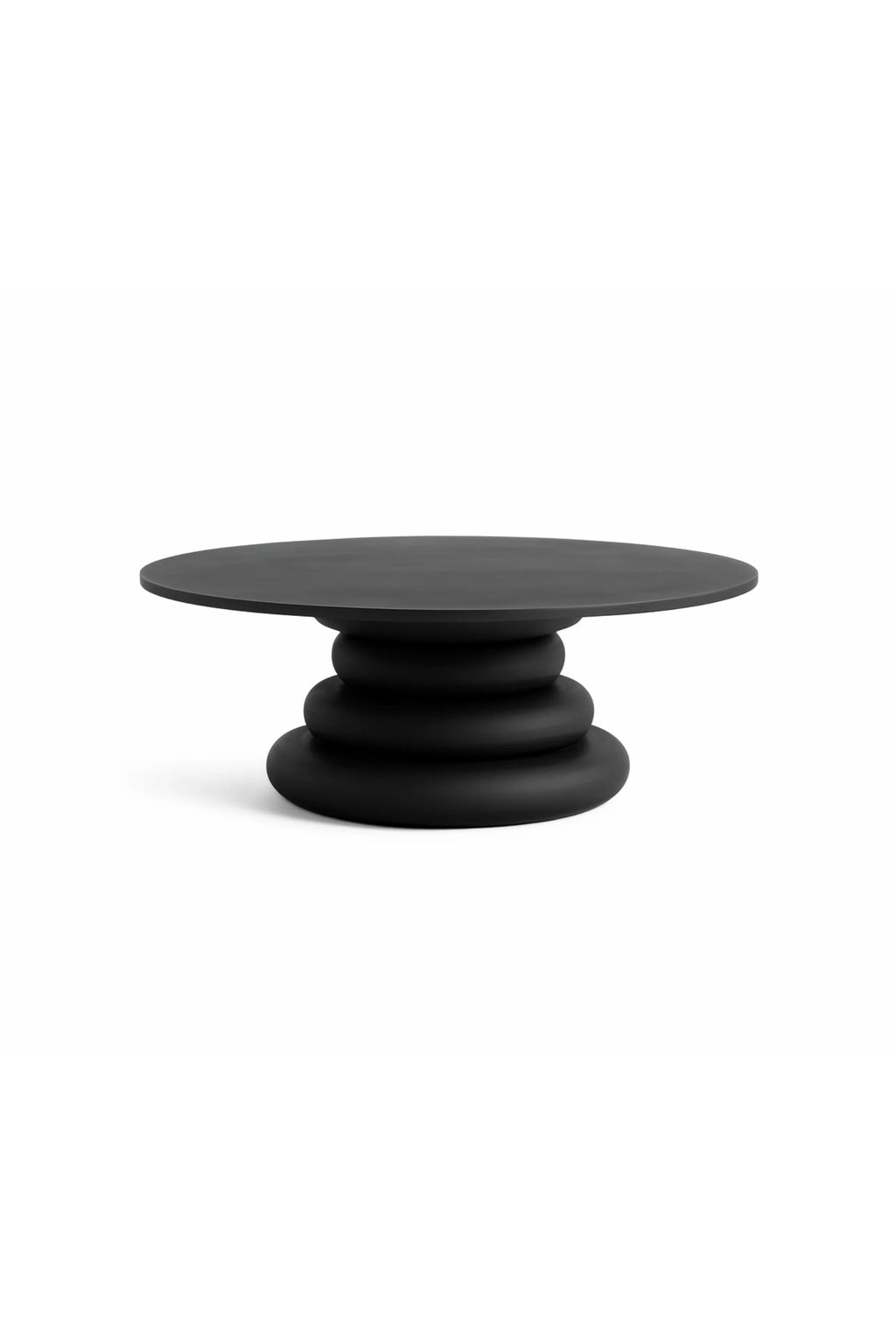 Nordal Yalu Coffee Table, a round matte black coffee table featuring a distinctive sculptural base composed of stacked, organic pebble-like forms. Crafted with a smooth, dark finish, this contemporary piece offers a minimalist aesthetic and bold presence. Perfect as a statement coffee table for modern living rooms or organic modern interiors.