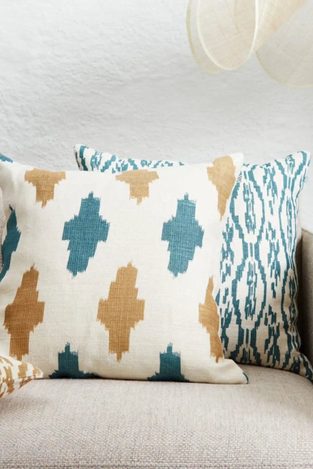 Chhatwal & Jonsson Deccan Linen Throw Pillow, a natural linen throw pillow featuring a striking geometric ikat pattern in vibrant teal and warm camel tones on a crisp cream background.