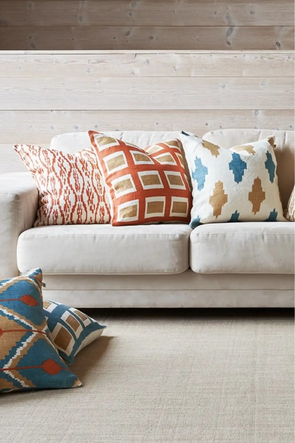 Chhatwal & Jonsson Deccan Linen Throw Pillow, a square hand-woven linen cushion featuring a global-inspired ikat pattern with repeating blue and tan geometric cross shapes on a natural cream background.