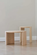 Two wooden stools on a light wood floor against a plain wall.