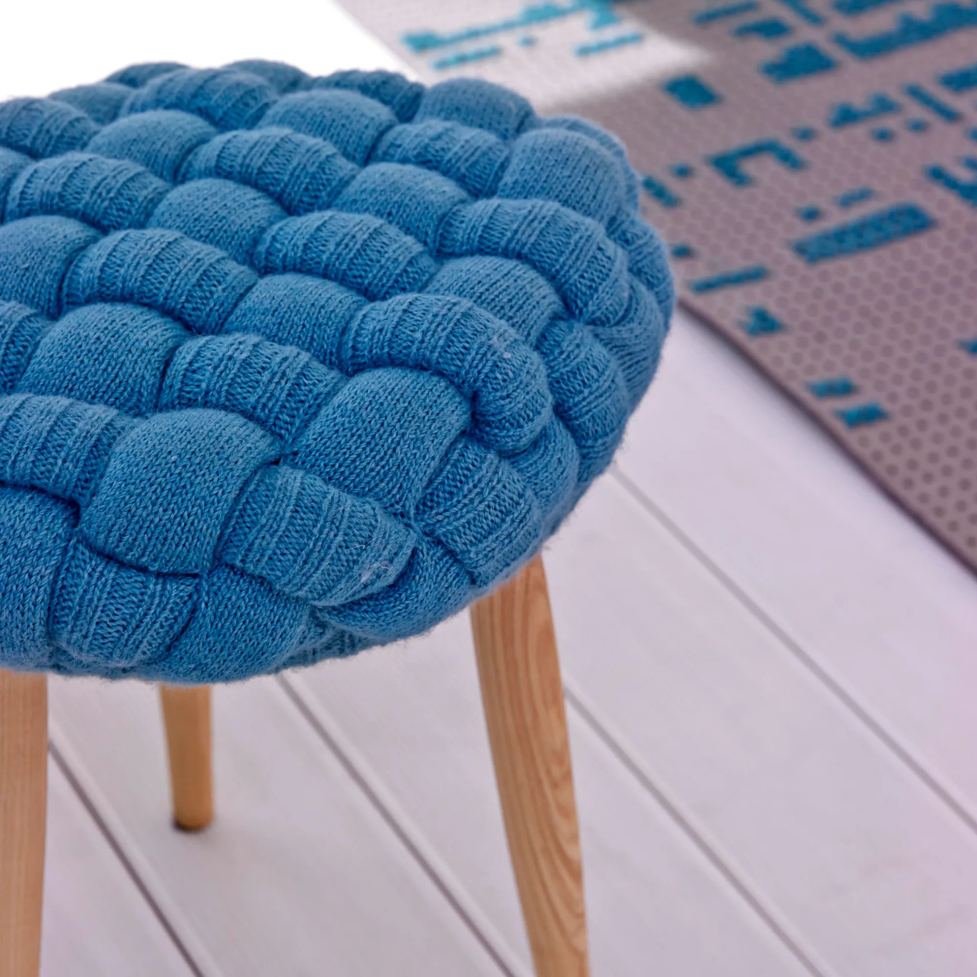 Cozy knitted stool in light blue perfect for adding warmth to any room