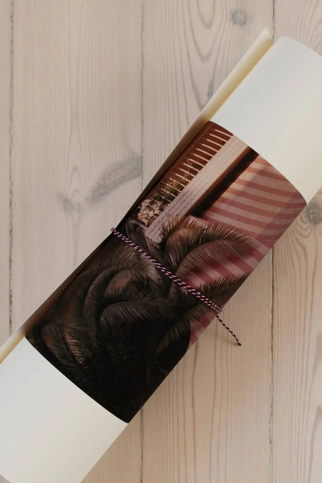 The Poster Club The Corner We Both Loved, a rolled photography art print showcasing a vibrant tropical scene with dark green palm fronds framing a sunlit building facade featuring warm wooden blinds and distinctive pink and.