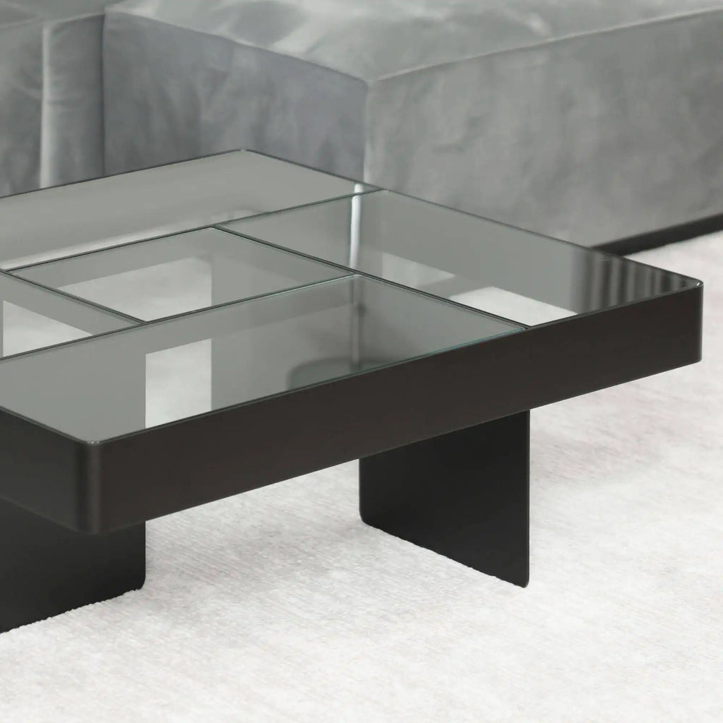 Around Works Blok Low Table, a modern minimalist coffee table featuring a square smoked glass tabletop divided into a grid pattern, supported by a sleek matte black metal frame and two solid block-like legs. This contemporary low table is ideal for adding a sophisticated geometric touch to modern living rooms or minimalist lounge areas.