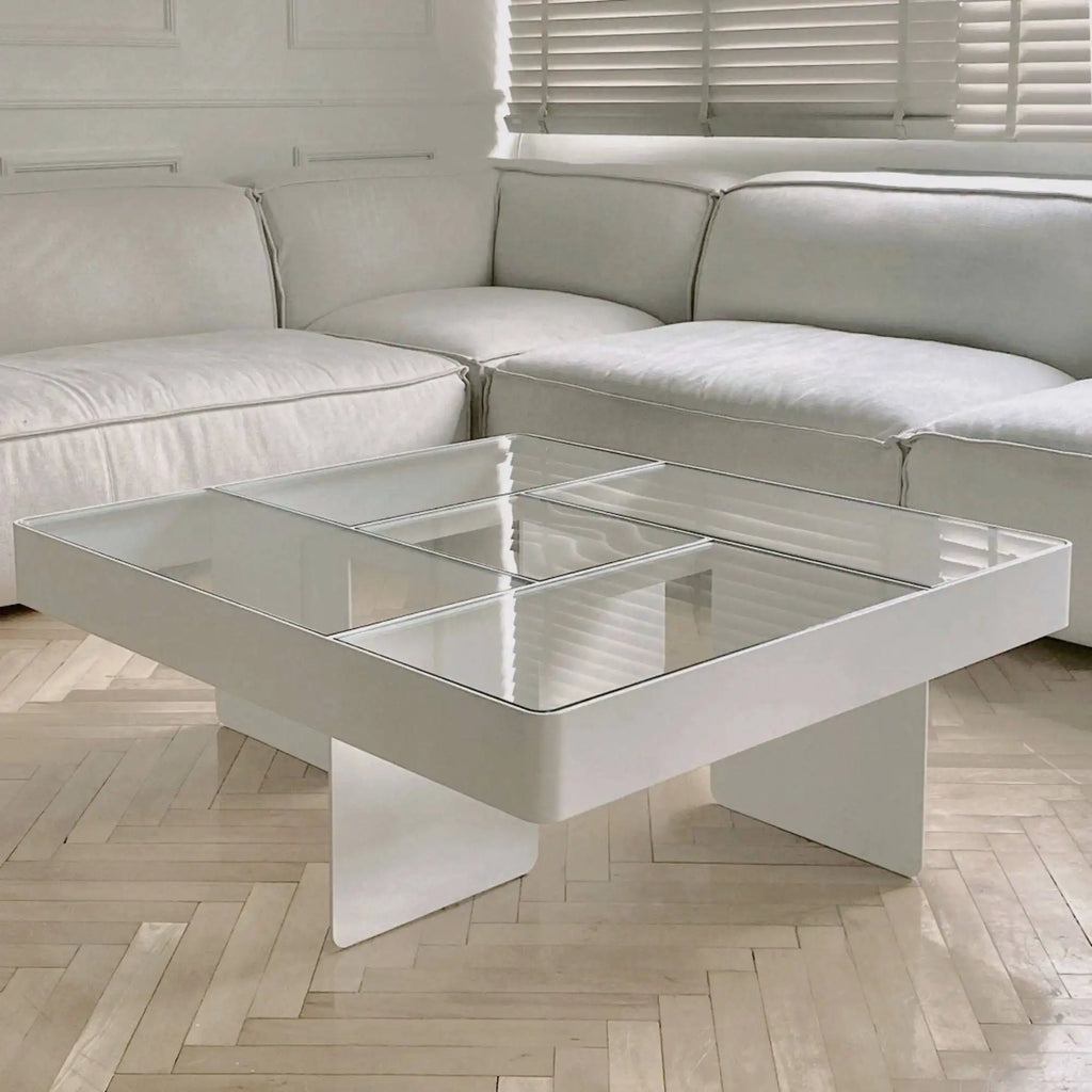 Around Works Blok Low Table, a modern minimalist white coffee table featuring a thick, rectangular white lacquered frame and a clear glass top divided into six square panels. Its clean lines and broad, angled white base create a striking geometric silhouette. Ideal for contemporary living rooms and minimalist design spaces.