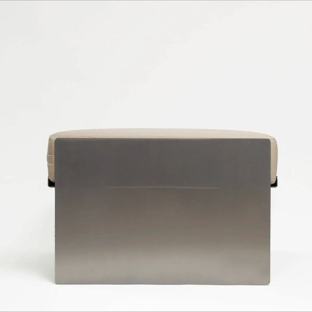Around Works C.01 Lounge, a modern minimalist pouf featuring a striking dark grey metal base with a matte finish and a plush, subtly segmented light greige upholstered fabric cushion.