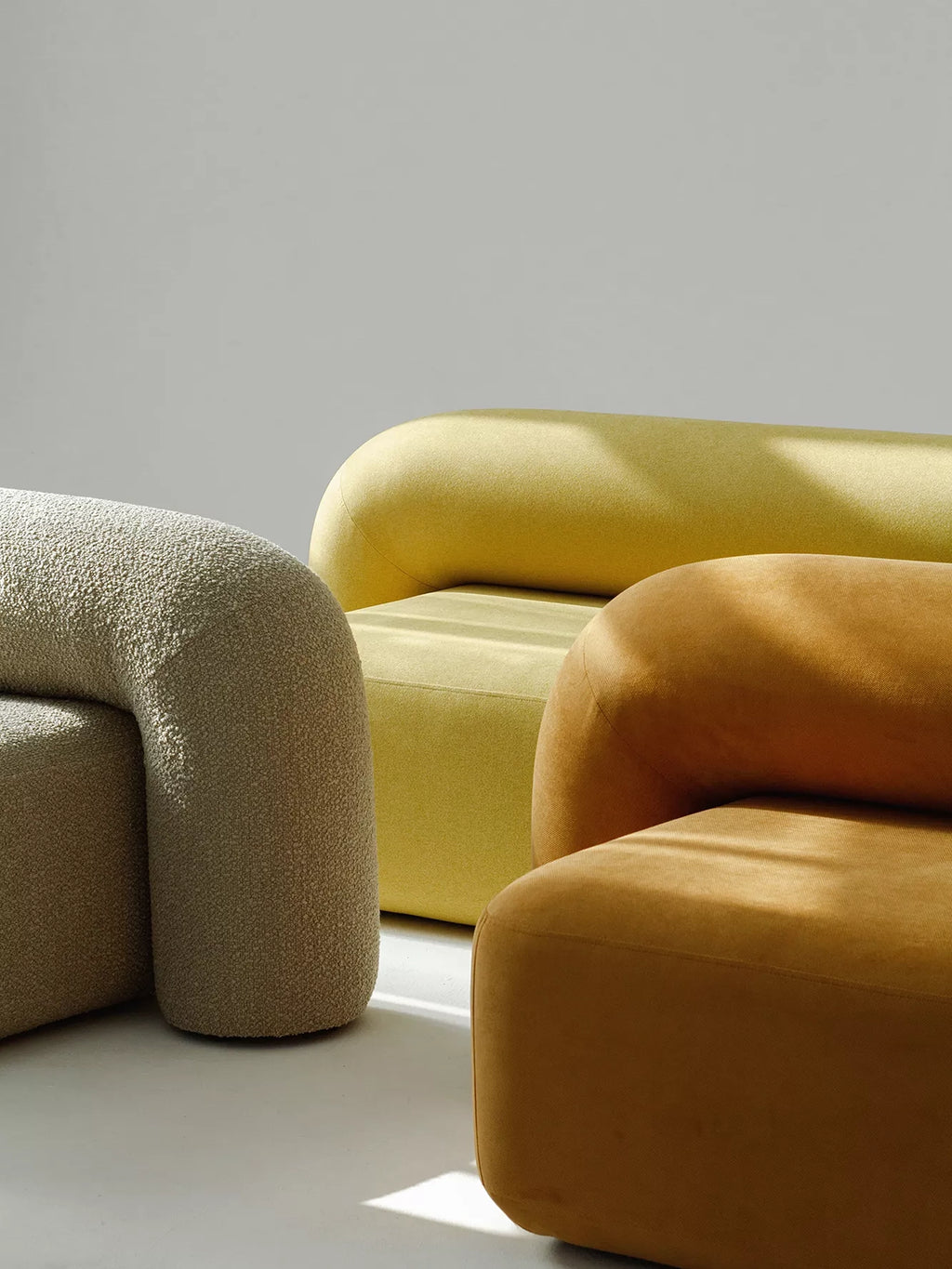 ARTU Moss Lounge Chair, a collection of organic modern lounge chairs featuring chunky, rounded, sculptural forms, upholstered in diverse textures like a light beige bouclé fabric and smooth velvet-like fabric.