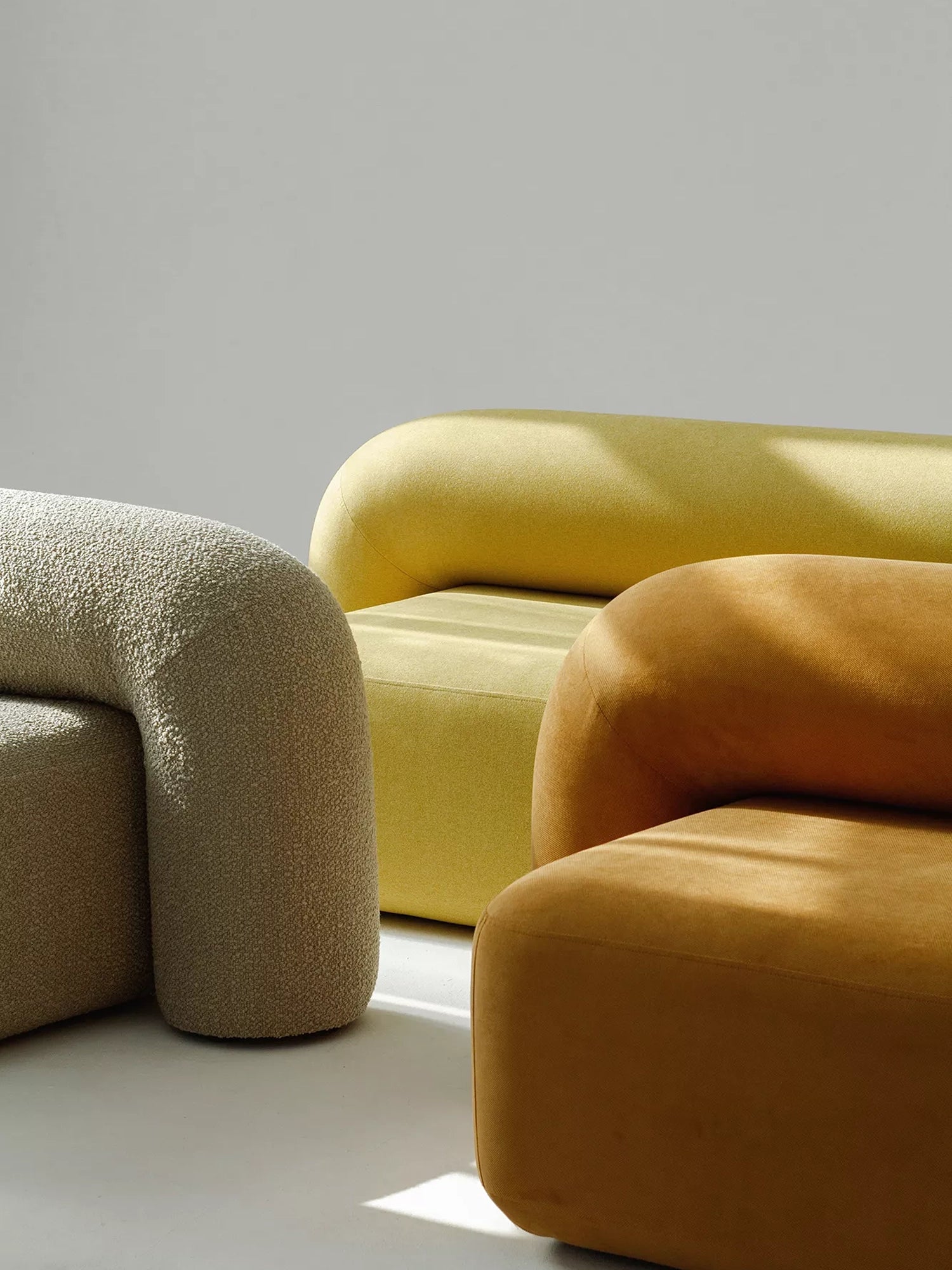 ARTU Moss Lounge Chair, a collection of organic modern lounge chairs featuring chunky, rounded, sculptural forms, upholstered in diverse textures like a light beige bouclé fabric and smooth velvet-like fabric.