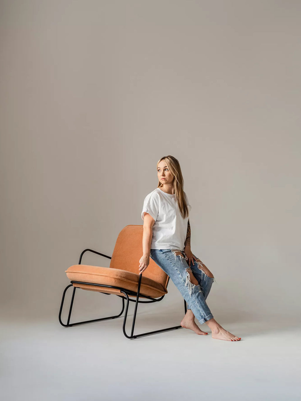 ARTU Tuttu Monteur Armchair, a contemporary lounge chair featuring rich terracotta textured fabric upholstery and a striking matte black metal frame. This industrial-chic accent chair boasts a unique open silhouette with gently curved legs and armrests, providing both modern style and comfortable seating. Perfect for minimalist living rooms, industrial style bedrooms, or a sophisticated home office.