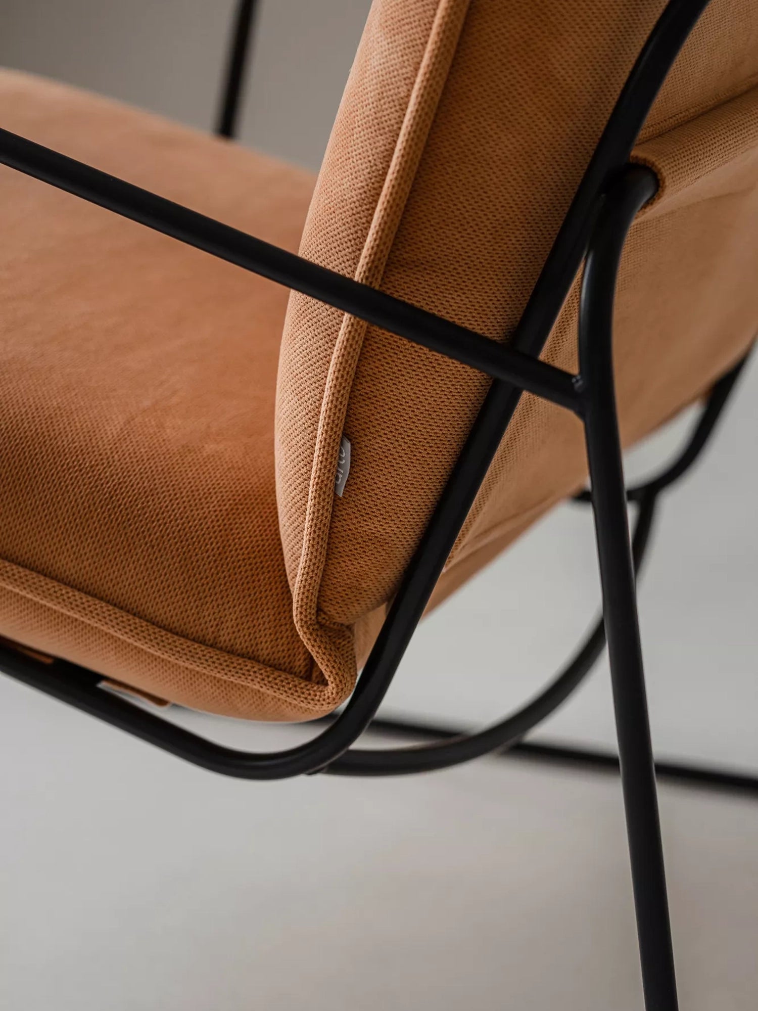 ARTU Tuttu Monteur Armchair, a contemporary lounge chair designed with a sturdy matte black metal frame and generously padded cushions upholstered in a rich terracotta woven fabric.