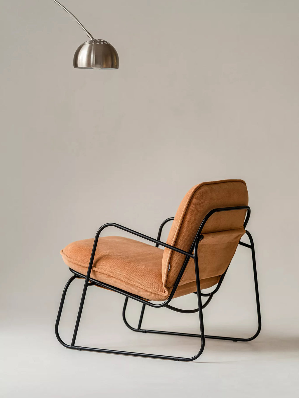 ARTU Tuttu Monteur Armchair, a contemporary industrial chic lounge chair featuring a sleek matte black tubular metal frame with a low-slung profile and comfortable, plush tan corduroy fabric upholstery. This modern minimalist armchair offers a relaxed seating experience, perfect for a stylish living room, cozy reading nook, or bedroom accent.