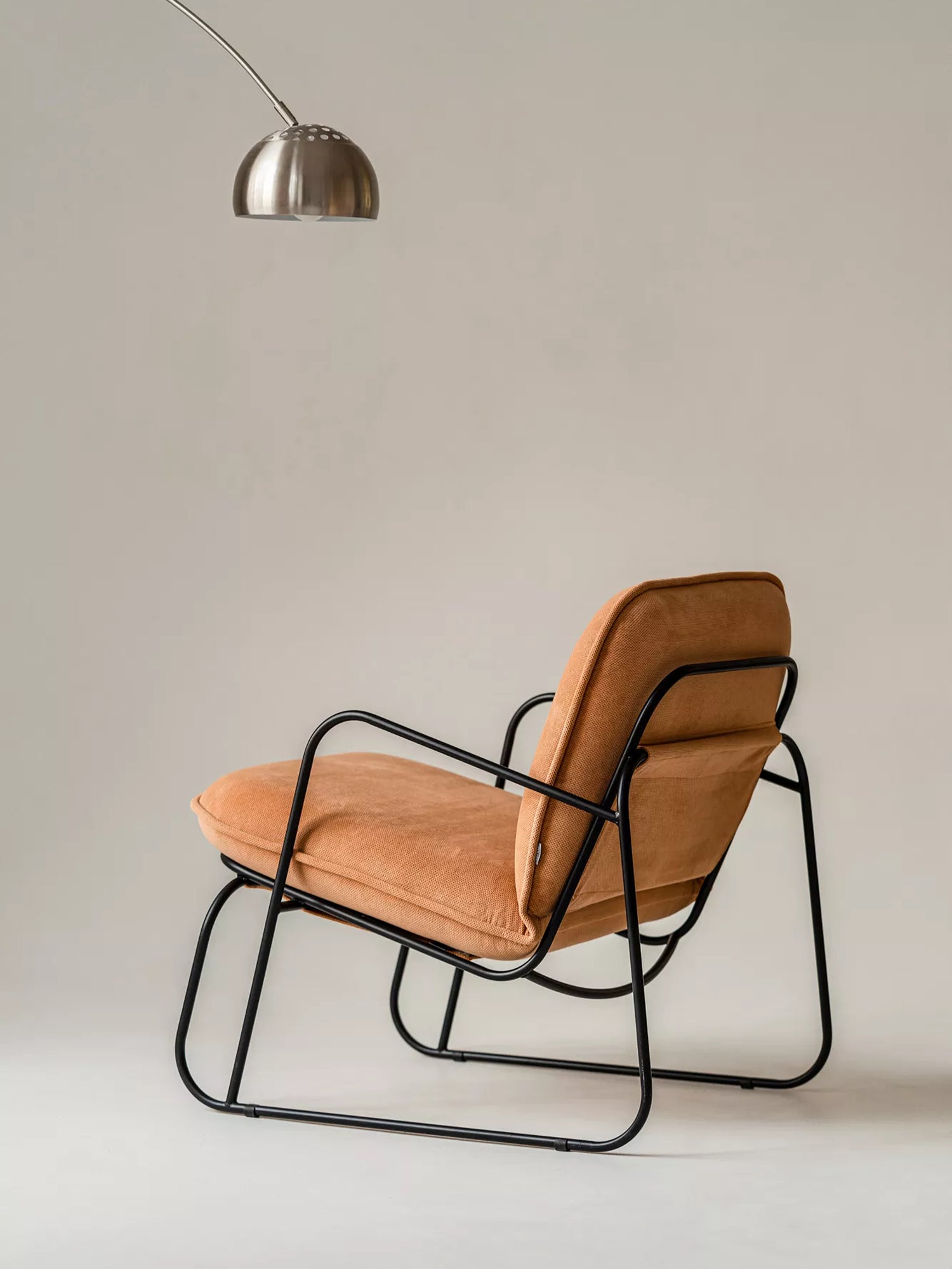 ARTU Tuttu Monteur Armchair, a contemporary industrial chic lounge chair featuring a sleek matte black tubular metal frame with a low-slung profile and comfortable, plush tan corduroy fabric upholstery. This modern minimalist armchair offers a relaxed seating experience, perfect for a stylish living room, cozy reading nook, or bedroom accent.