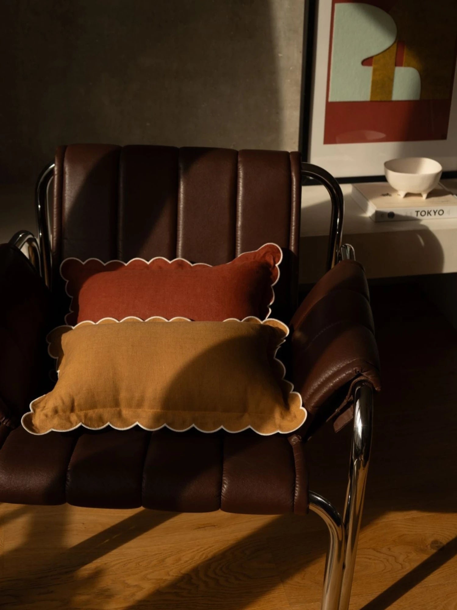 Brown leather chair with two decorative pillows in a room setting.