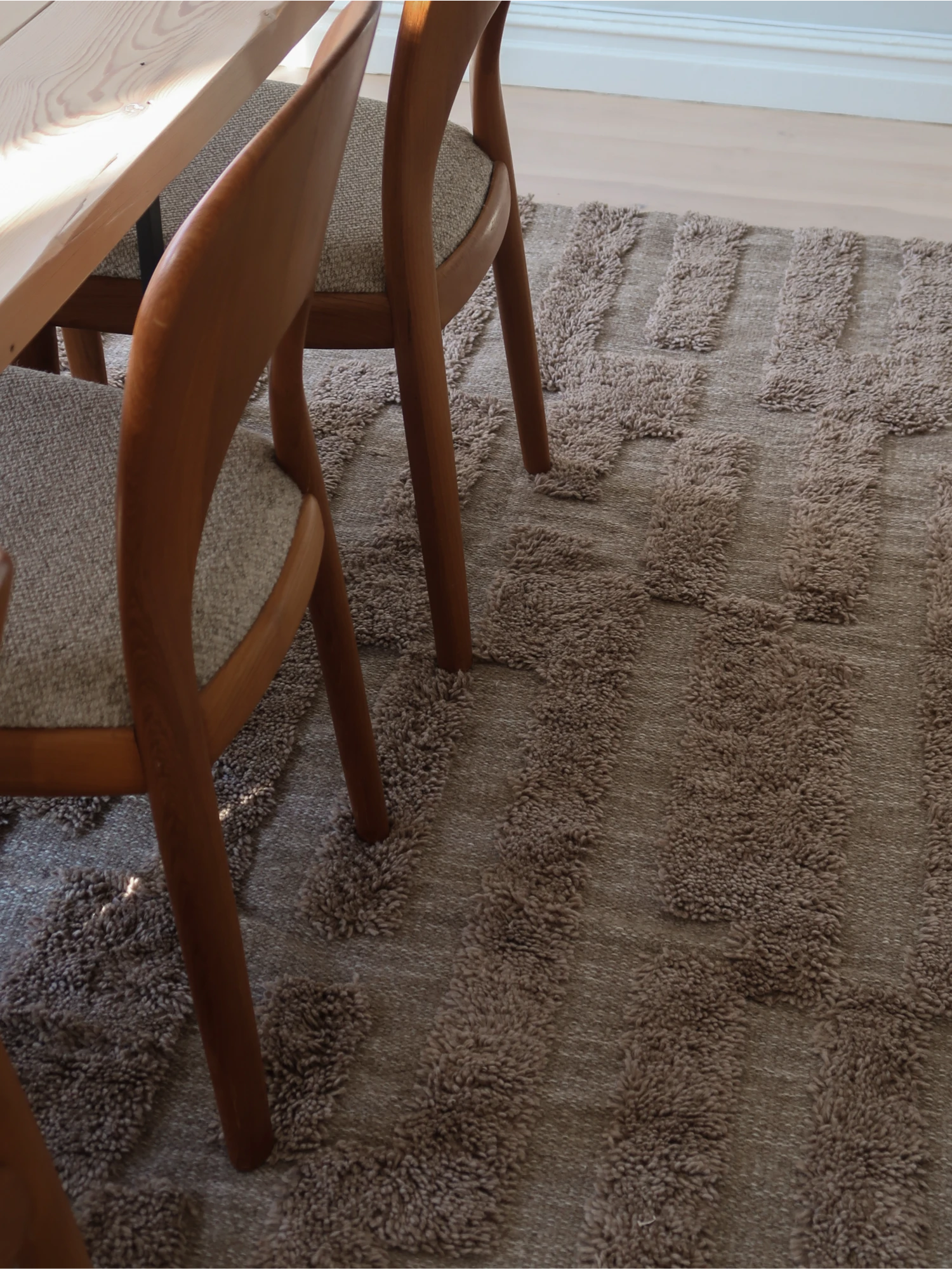 Tinted Objects Bielke Wool Rug, a plush, textured taupe rug with a distinctive raised geometric pattern. This durable, soft area rug is perfect for adding warmth and modern style to living rooms or dining areas.
