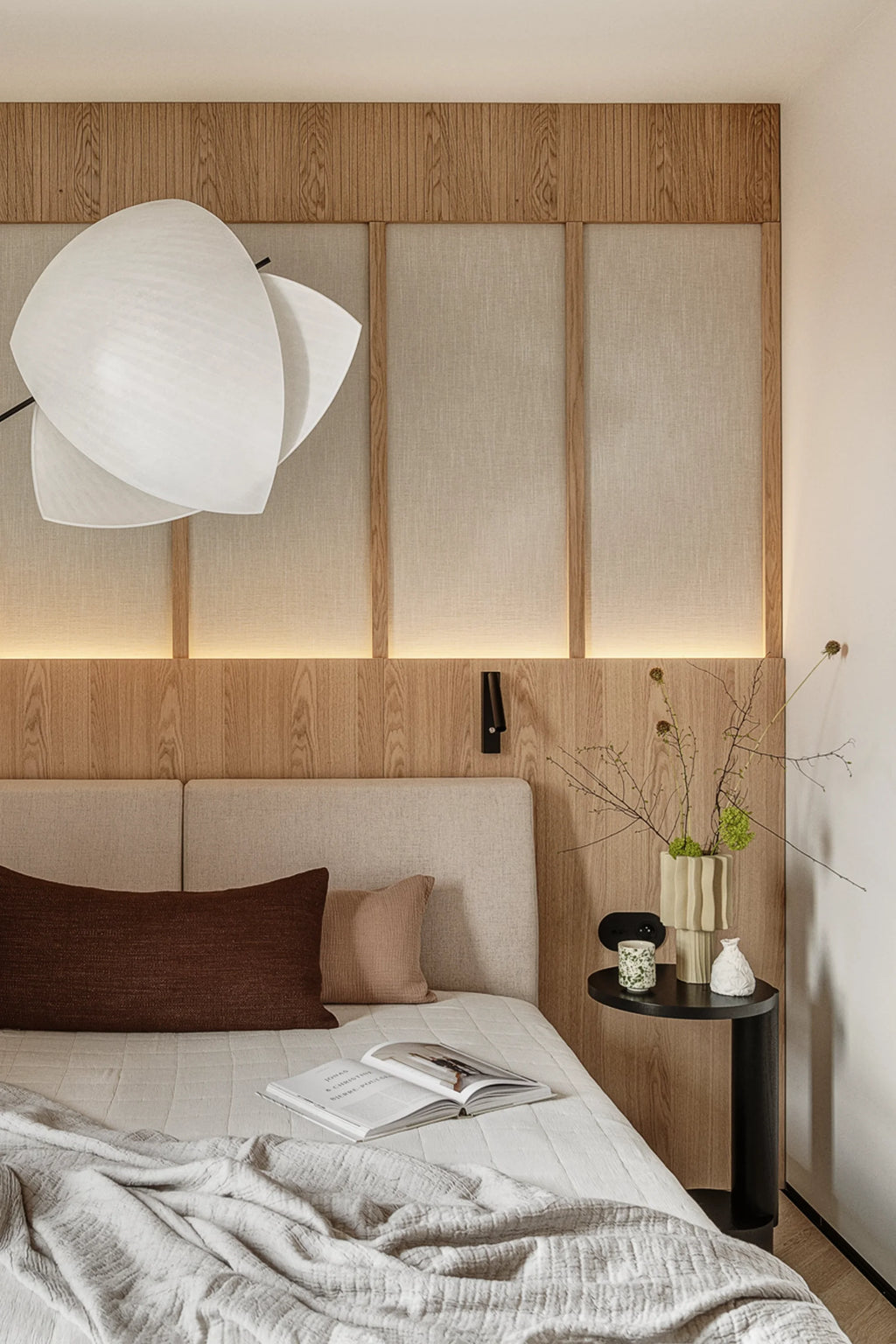 TAMO Bold Side Table: A sleek, modern black wooden C-shaped side table with a semi-circular top and round base, styled with neutral decor items by a bed. A premium contemporary accent for any bedroom.
