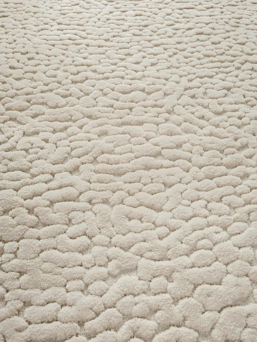 alp_ Borneo Rug, a natural cream-colored area rug featuring a distinct organic pebble texture with a plush, high-pile shaggy surface, offering exceptional softness.