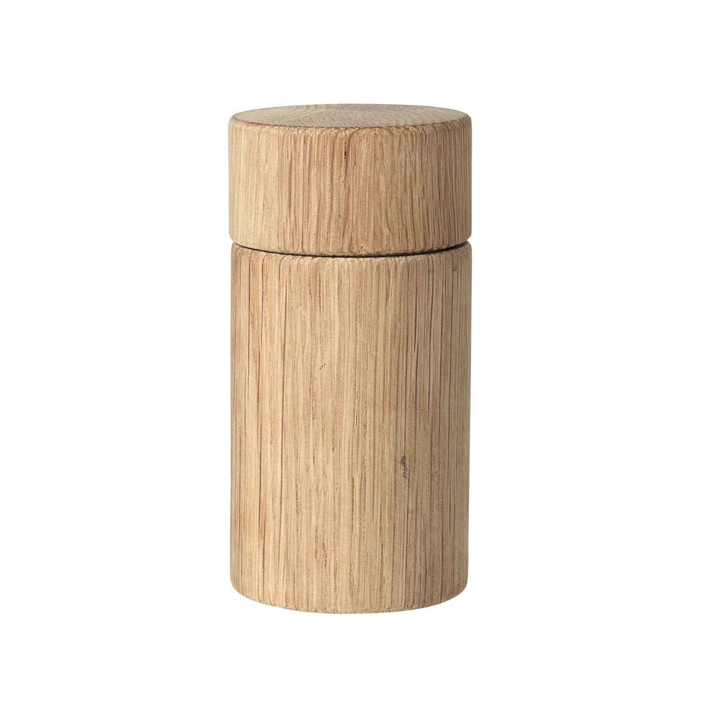 Broste Copenhagen Oak Grinder, a minimalist cylindrical spice grinder crafted from natural solid oak wood with a visible vertical wood grain texture and a light, warm brown finish. This Scandinavian-inspired oak pepper mill is perfect for modern kitchen decor or as a stylish dining table accessory.