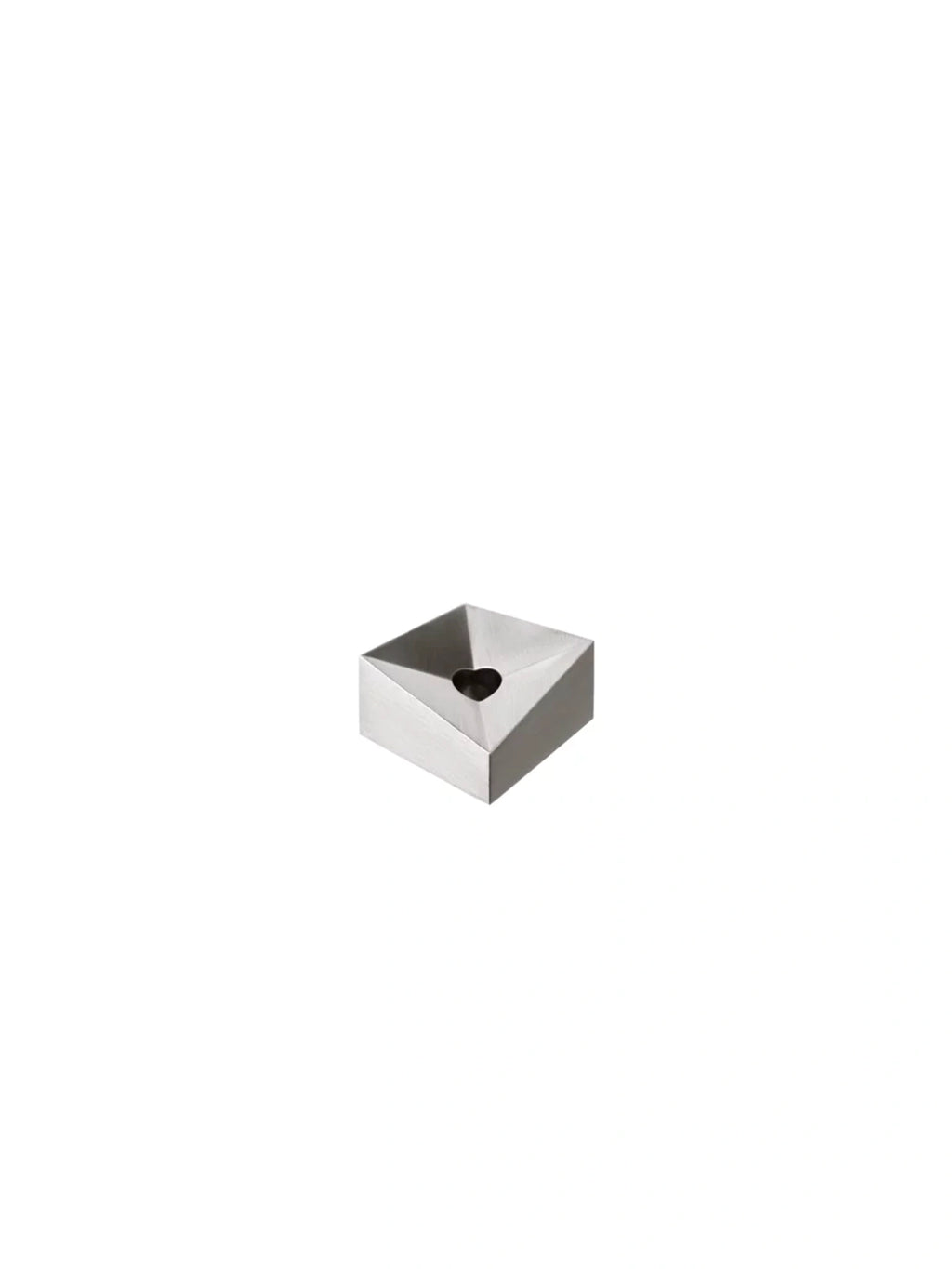 Stoff Nagel Reflect Candle Holder, a sleek modern sculptural candle holder crafted from polished chrome metal with an angular, faceted square base and a distinctive heart-shaped opening. This silver metal geometric design offers a brilliant, reflective finish. Ideal for minimalist shelf styling, contemporary living room accents, or as a unique dining table centerpiece.