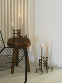 Handmade candles in stoff nagel candle holders on top of a wooden mid-century modern designer stool.
