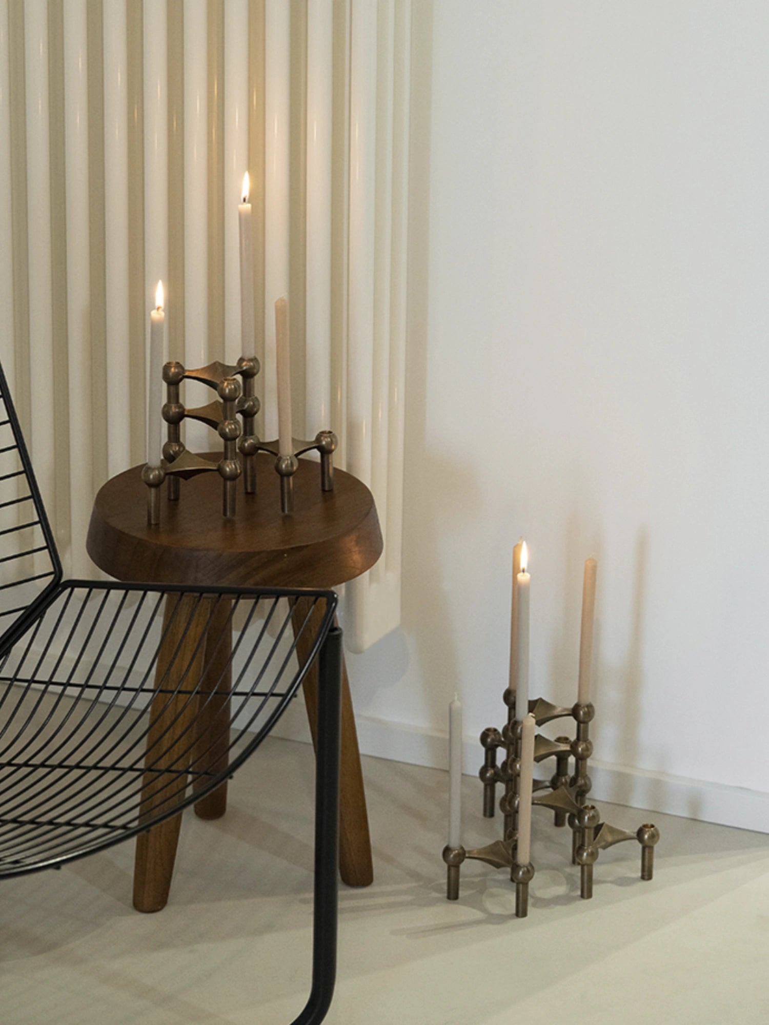 Handmade candles in stoff nagel candle holders on top of a wooden mid-century modern designer stool.
