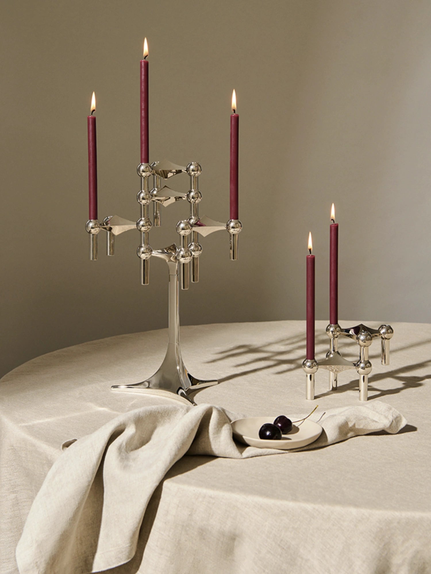 Stoff Nagel Candles - Set of 12, featuring slender deep red taper candles with a smooth wax finish, designed to perfectly complement the iconic Stoff Nagel modular candlestick holders. These elegant burgundy dinner candles are ideal for creating a sophisticated dining table centerpiece or adding a touch of warmth to modern minimalist and brutalist-inspired living room decor.