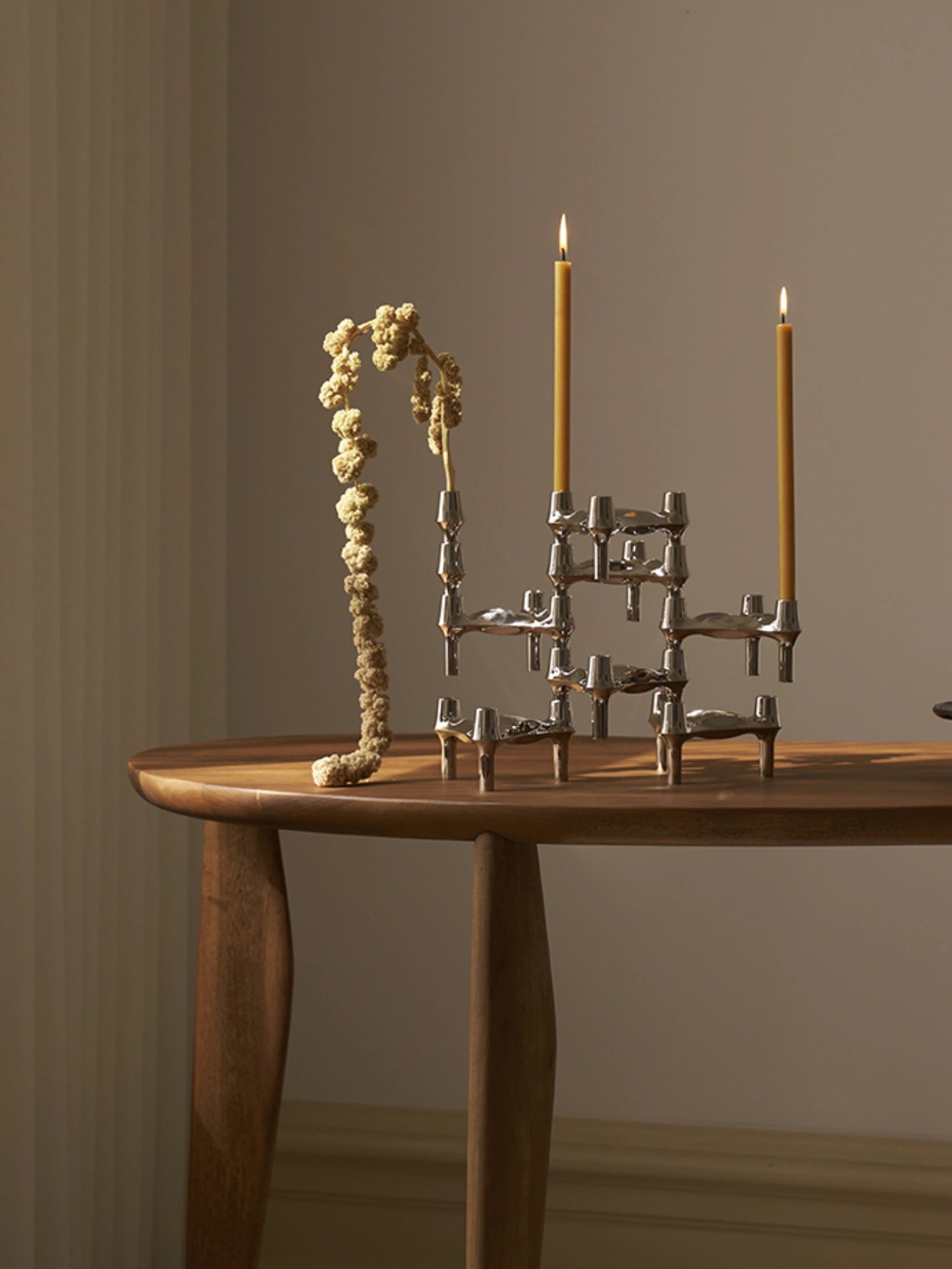 Decorative candles in the iconic stoff nagel candle holders on top of a wooden designer dining table. Set of 8.