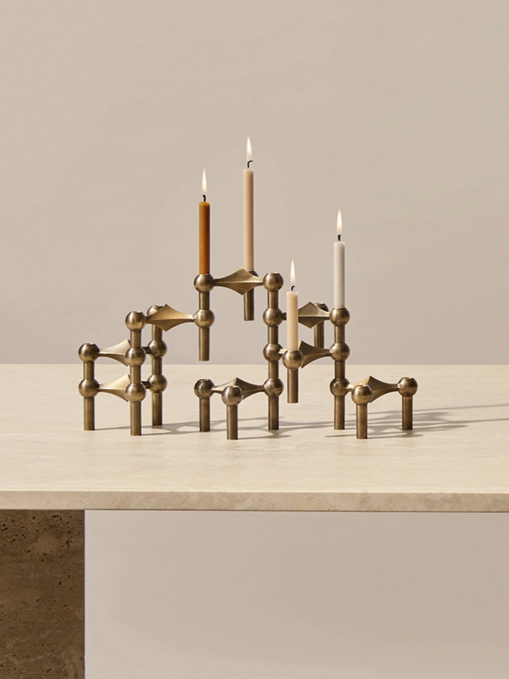 different color stoff nagel candle holder in the iconic stoff nagel candle holder on top of a travertine dining table.