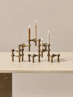 different color stoff nagel candle holder in the iconic stoff nagel candle holder on top of a travertine dining table.