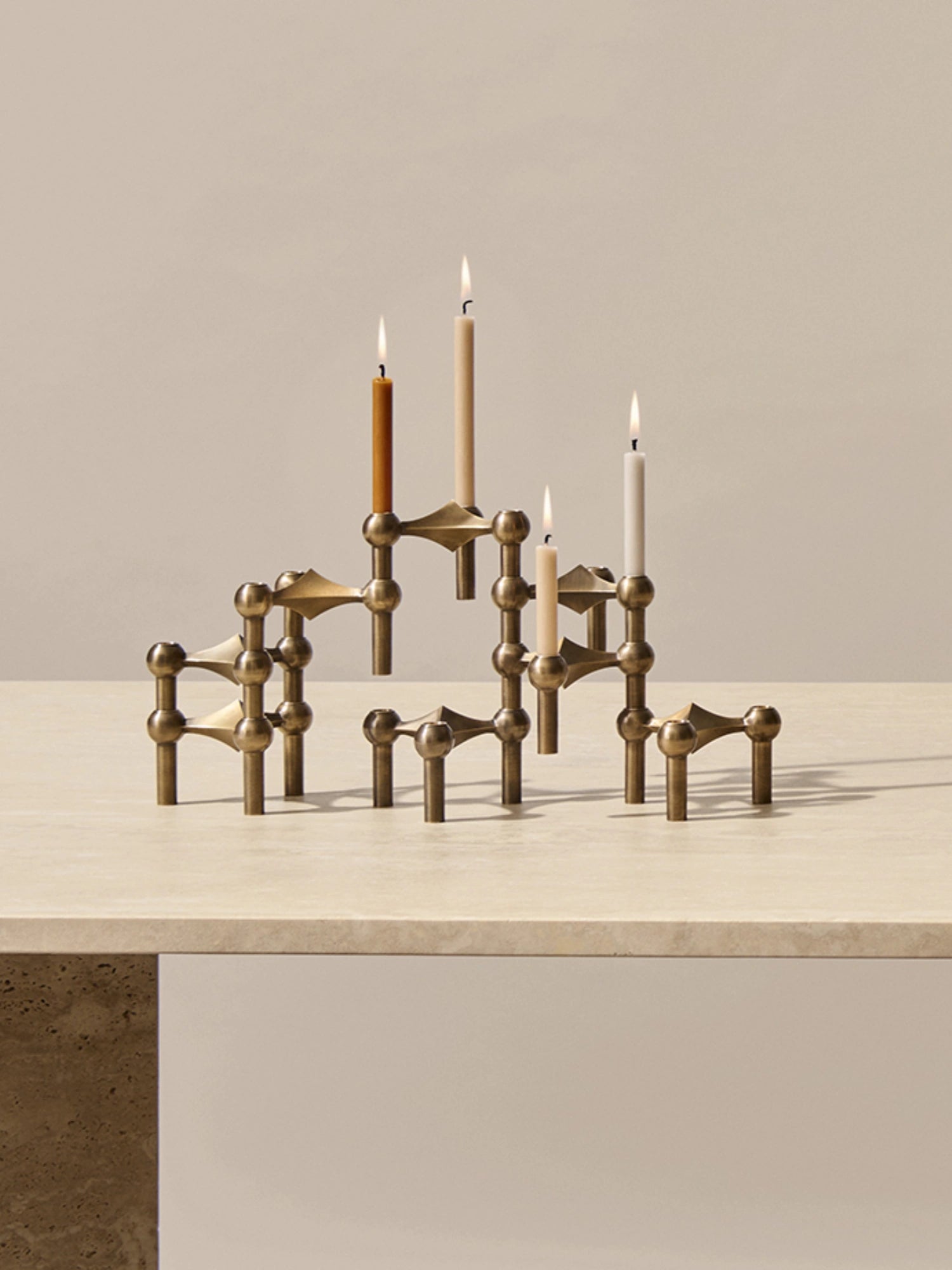 different color stoff nagel candle holder in the iconic stoff nagel candle holder on top of a travertine dining table.