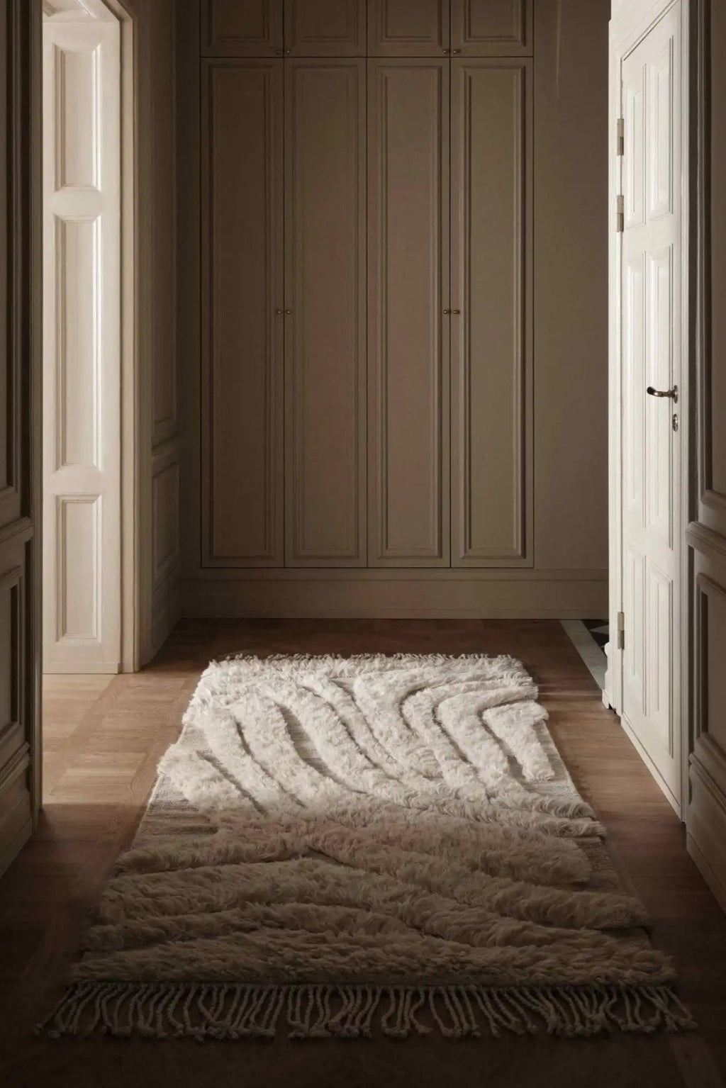 Cappelen Dimyr Colonnade No.01 Rug, a luxurious natural ivory hand-knotted wool rug featuring a high pile shaggy texture with a distinct wavy, sculptural pattern. This organic modern rug offers plush comfort and visual interest, perfect for a contemporary hallway runner or a cozy Scandinavian living room accent.