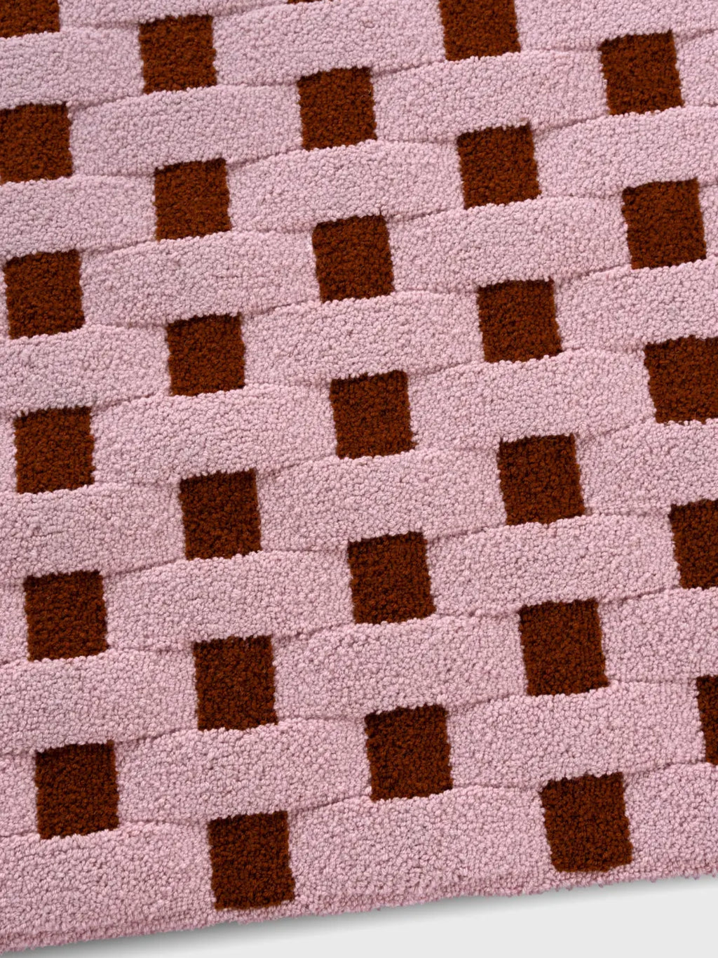 alp_ Cesta Rug, a playful contemporary area rug crafted from a soft cotton blend with a plush tufted pile, featuring an interlocking basketweave pattern in muted blush pink and rich terracotta brown.
