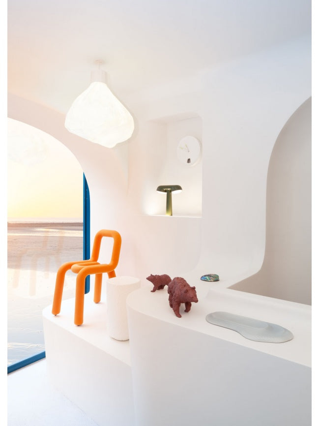 Moustache Bold Chair, a vibrant orange contemporary chair featuring a distinctive continuous tubular steel frame entirely upholstered in soft, padded foam for a sculptural and playful silhouette. This bold accent chair is perfect for adding a pop of color and modern design to living rooms, dining areas, or creative office spaces.