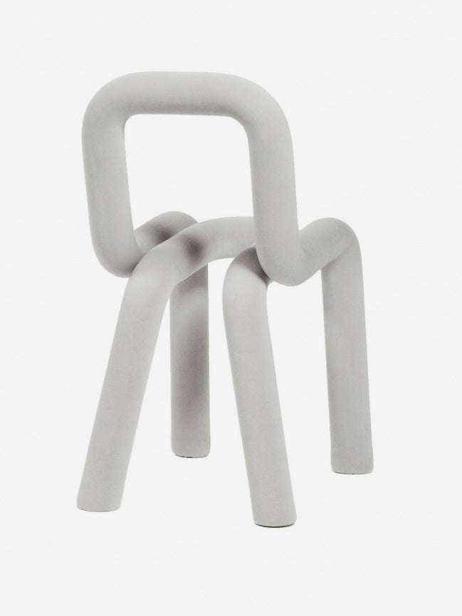 Moustache Bold Chair, a modern sculptural accent chair featuring a continuous tubular design crafted from foamed steel tubes with a soft, matte pale grey finish.