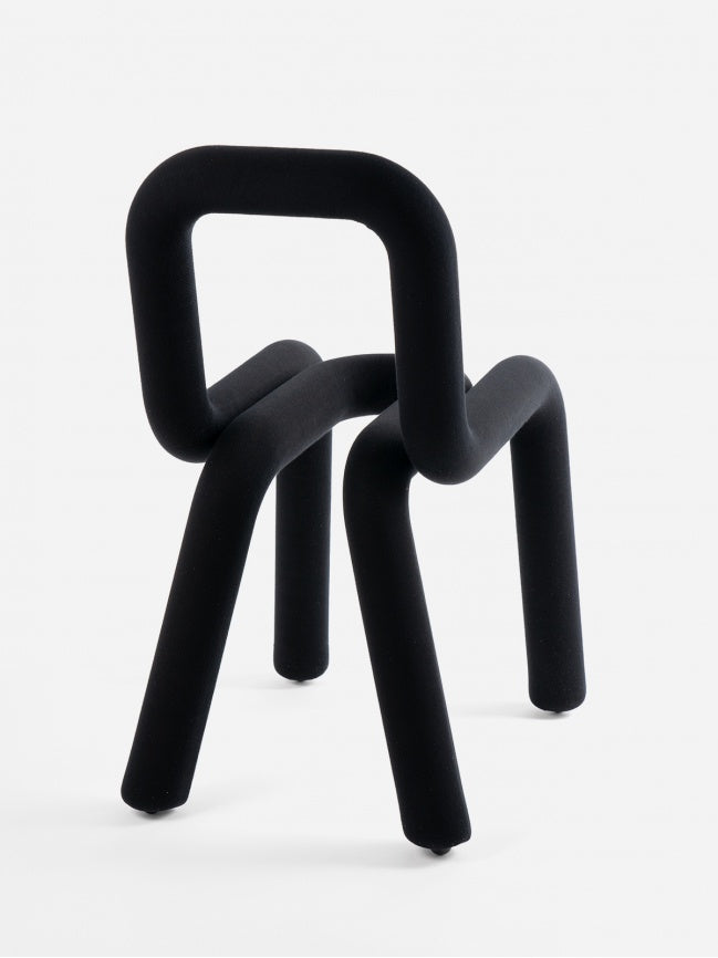 Moustache Bold Chair, a striking contemporary sculptural chair crafted from a continuous tubular steel frame, fully upholstered in a soft, matte black velvet-like flocked textile. Its bold, minimalist design features exaggerated rounded curves and an abstract silhouette, creating a playful yet sophisticated statement piece. Ideal as a designer dining chair, avant-garde accent chair for modern living rooms, or a unique art object in contemporary interiors.