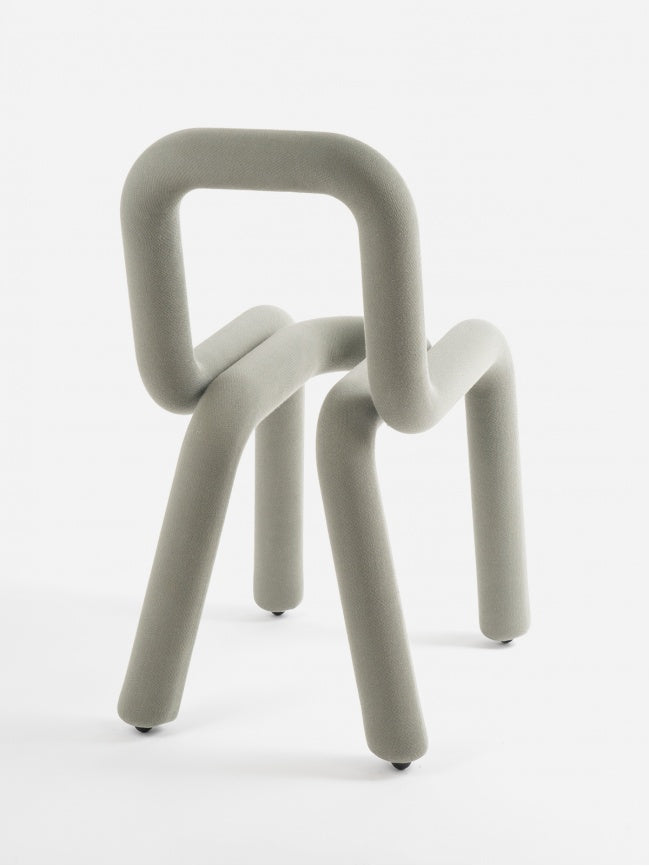 Moustache Bold Chair, a contemporary sculptural dining chair crafted from a continuous tubular steel frame, generously padded and upholstered in a pale sage green textured fabric.