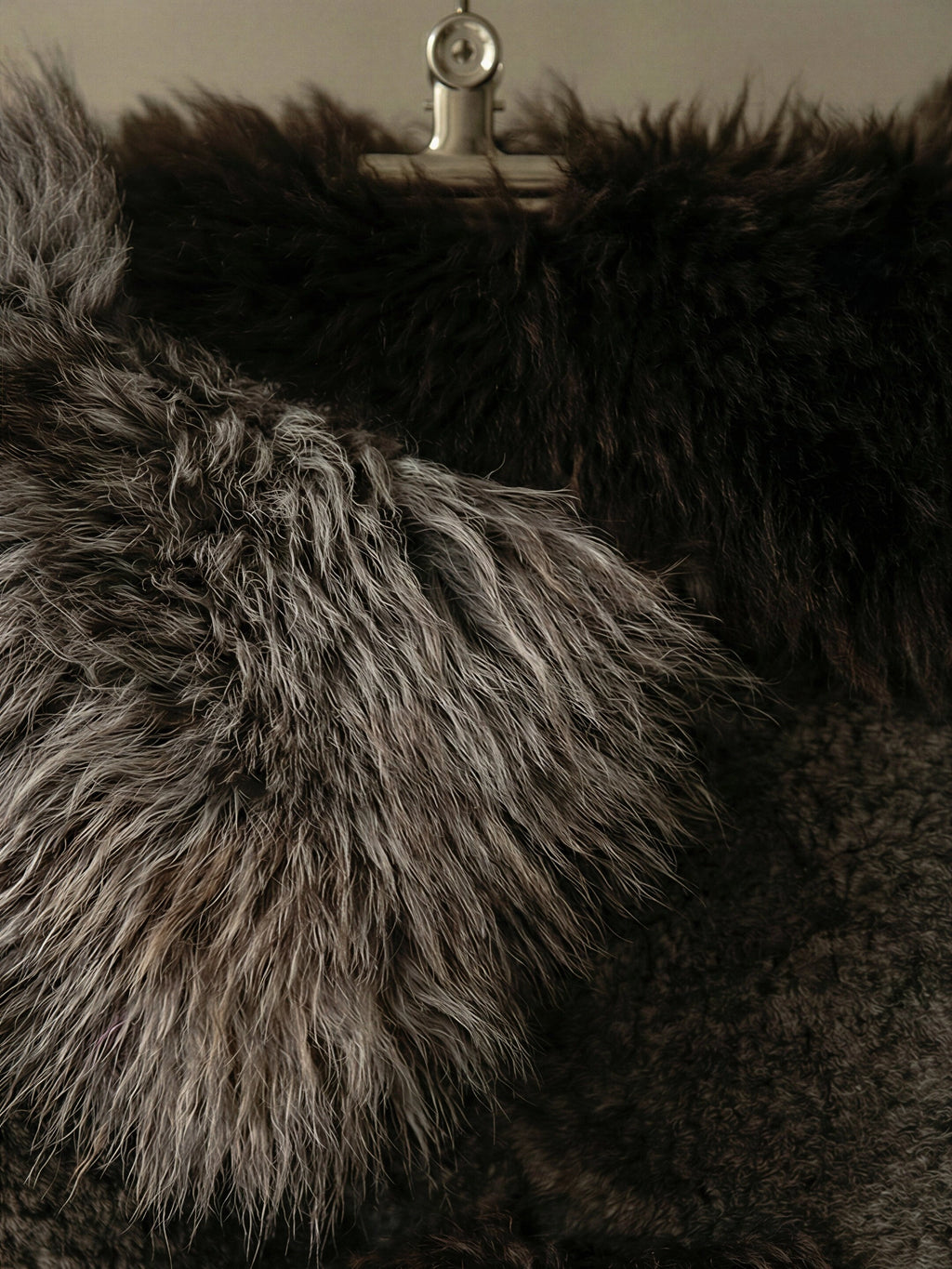 TCL Studios Brown Sheepskin Patchwork Rug, a luxurious long-pile sheepskin rug in rich dark brown and silvery-grey brown tones, featuring a shaggy, soft texture. Crafted from genuine sheepskin pieces, it's perfect for adding warmth and organic style to rustic, Scandinavian, or organic modern living rooms and bedrooms.