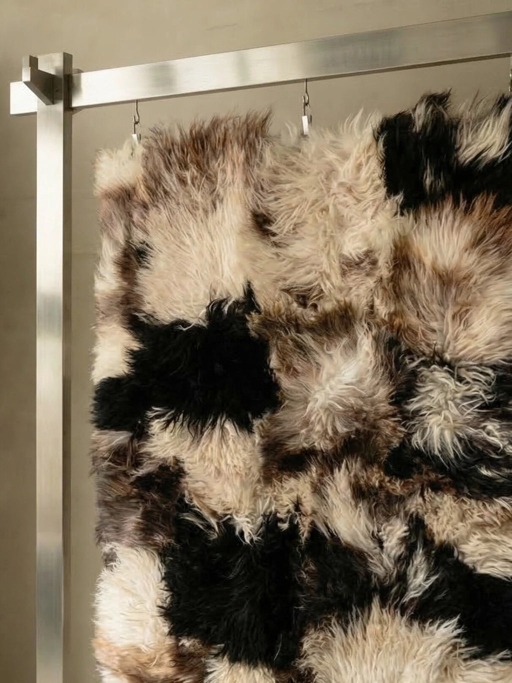 TCL Studios Curly Sheepskin Patchwork Rug, a luxurious and plush natural sheepskin area rug featuring a shaggy, curly texture in a striking patchwork design of black, creamy white, and warm brown tones.