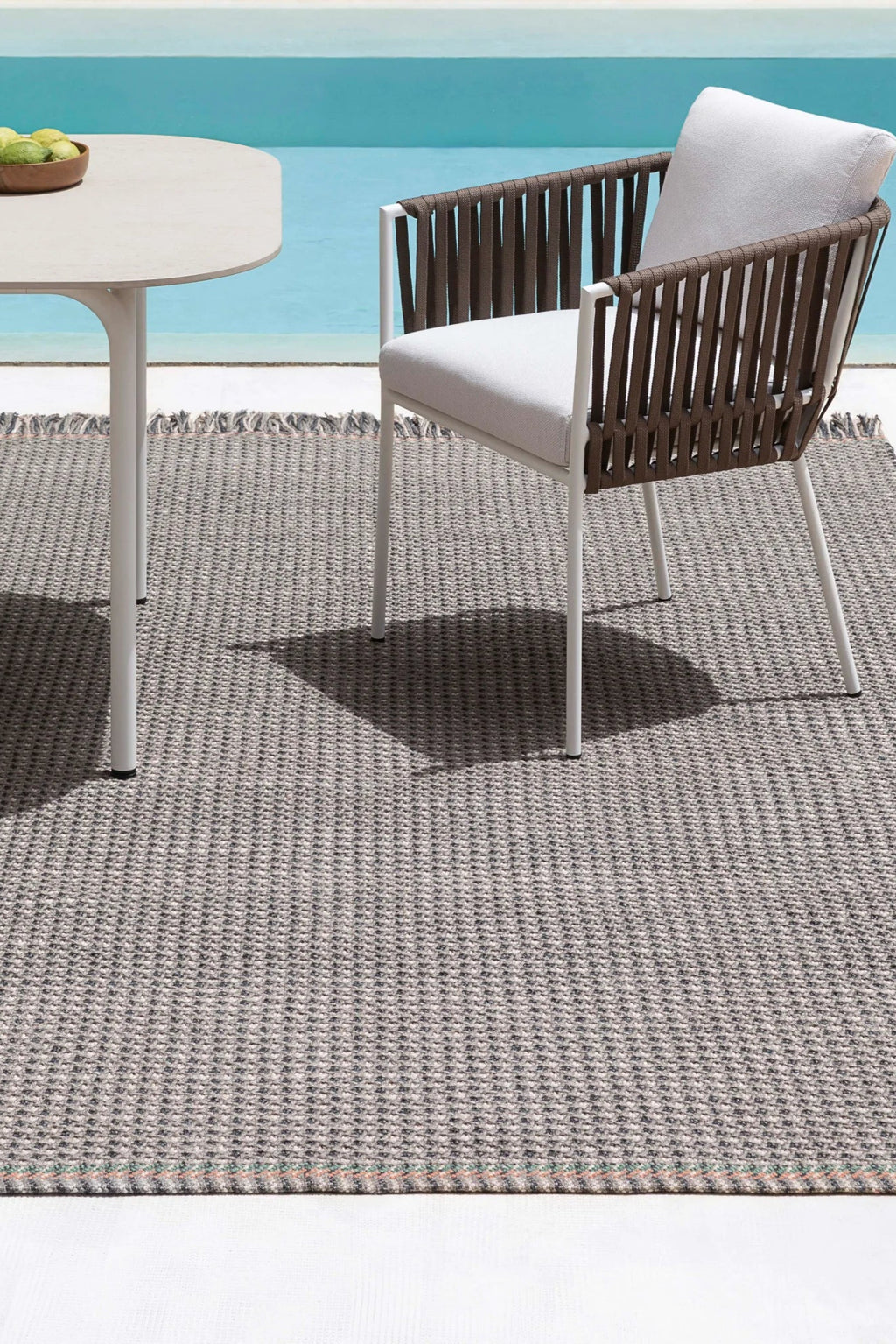 Gandia Blasco Corda Outdoor Dining Chair, a contemporary outdoor chair featuring a sturdy white powder-coated aluminum frame with a distinctive brown woven cord backrest and armrests, complemented by plush light grey upholstered outdoor cushions. This modern patio chair is perfect for stylish poolside dining, terrace areas, or sophisticated outdoor living spaces.