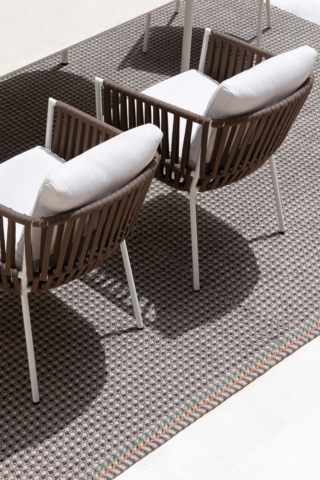 Gandia Blasco Corda Outdoor Dining Chair, a contemporary design featuring a curved body crafted from durable brown woven cord with a sturdy white powder-coated aluminum frame and sleek legs. It includes plush light grey outdoor fabric cushions for comfort and style. This modern outdoor chair is ideal for sophisticated patio dining sets, garden seating, or a minimalist balcony.