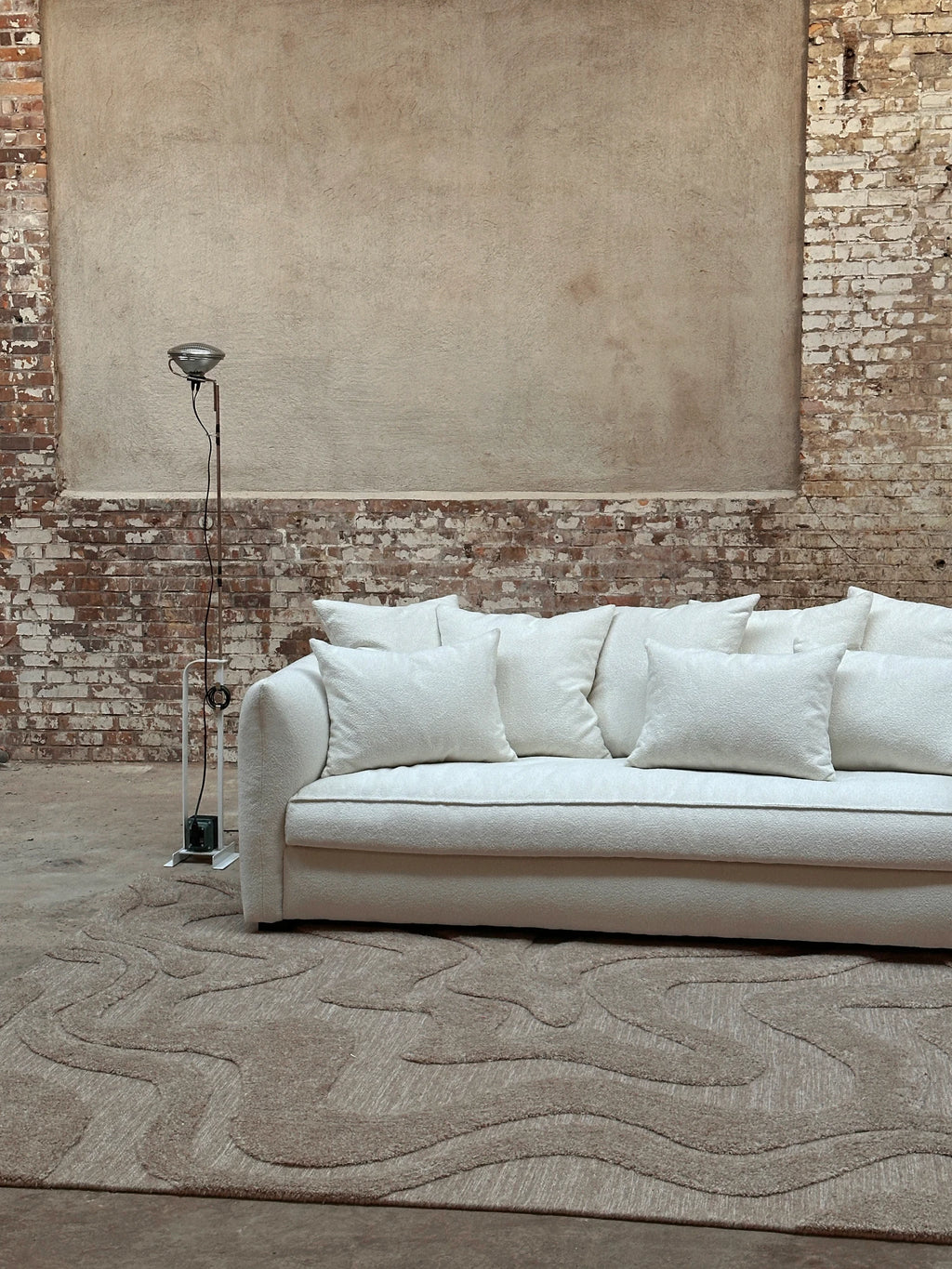 Tinted Objects Cornell Sofa, a contemporary cream bouclé fabric sofa featuring plush, textured upholstery and a modern low-profile design with soft, inviting curves. This luxurious sofa offers deep seating and comes with multiple matching throw pillows, perfect for creating an organic modern aesthetic in a minimalist living room or a cozy, stylish lounge space.