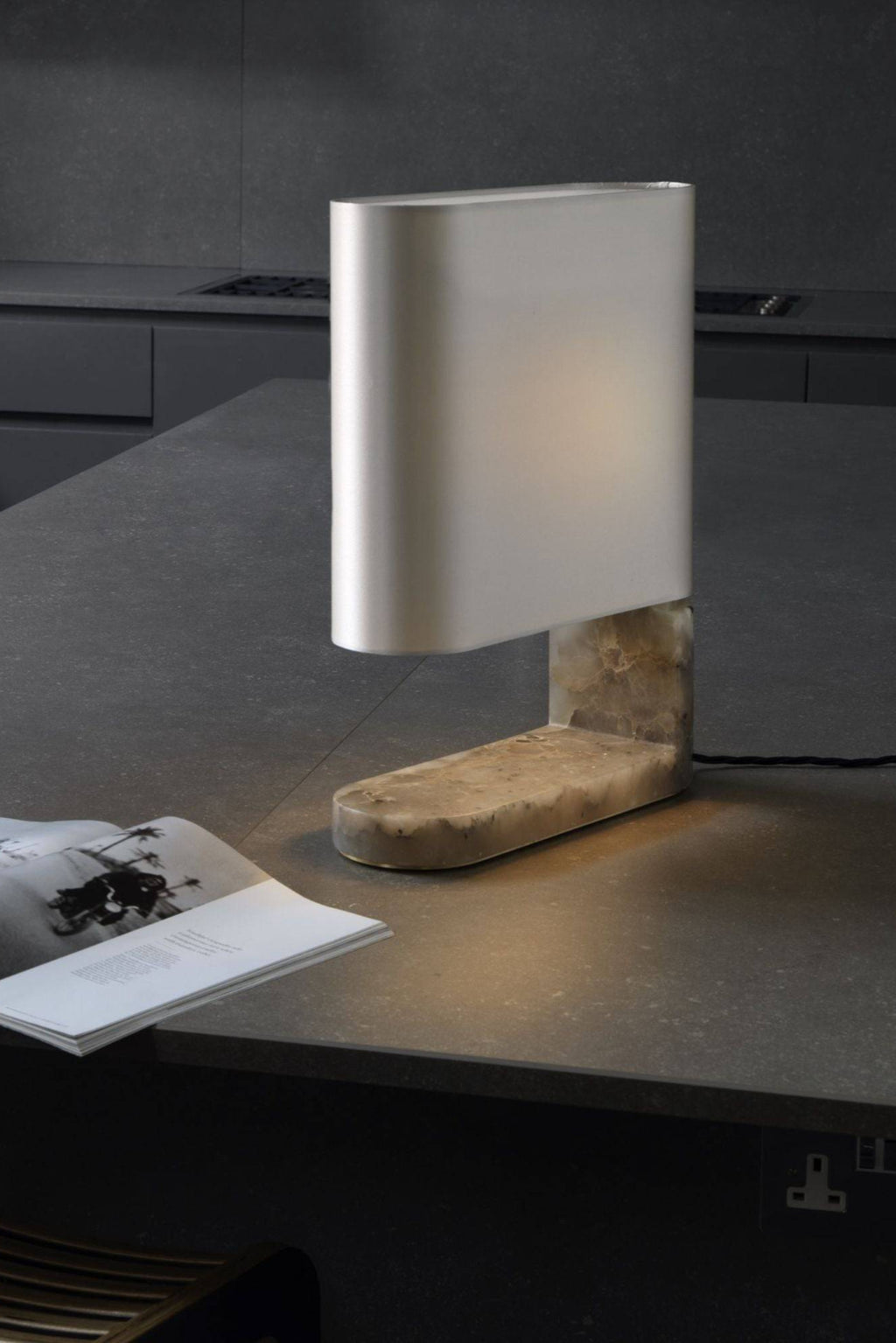 CTO Lighting Columbo Table Lamp, a sophisticated modern table lamp featuring a rectangular frosted white glass shade that emits a soft ambient glow. It rests on a distinctive L-shaped base crafted from natural veined cream marble, showcasing an elegant organic texture. This luxury contemporary table lamp is ideal for adding minimalist elegance to a living room side table, home office desk, or modern bedroom.