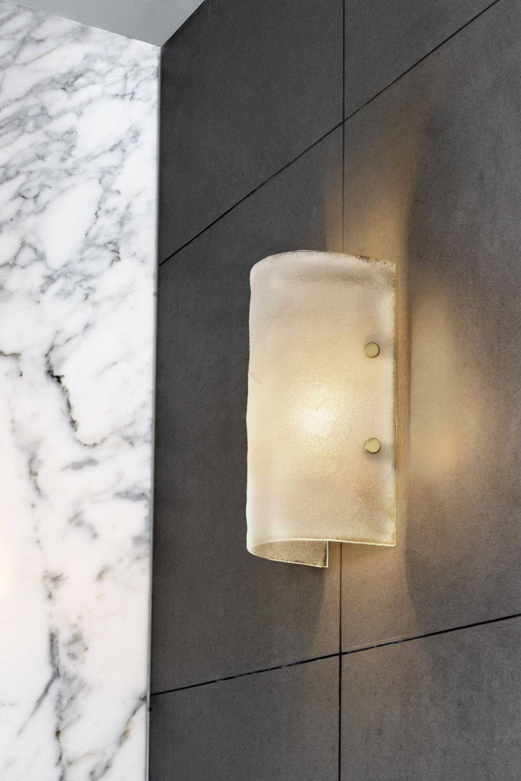 CTO Lighting Whistler Wall Lamp, a luxurious contemporary wall sconce featuring a curved, textured frosted glass diffuser in a warm cream hue, secured by elegant brass fixings. This modern wall light provides soft, ambient illumination, perfect for adding sophisticated accent lighting to a living room, bedroom, or luxury bathroom.