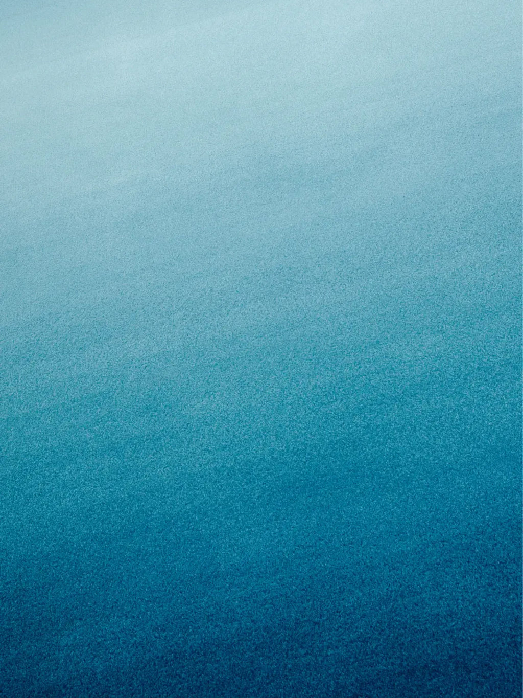 alp_ Degradé Double Rug, a modern blue ombre area rug featuring a plush, soft textured pile with a beautiful gradient transitioning from serene light blue to a deep teal. This contemporary wool rug is perfect for adding a coastal touch to living rooms or creating a calming atmosphere in bedrooms.