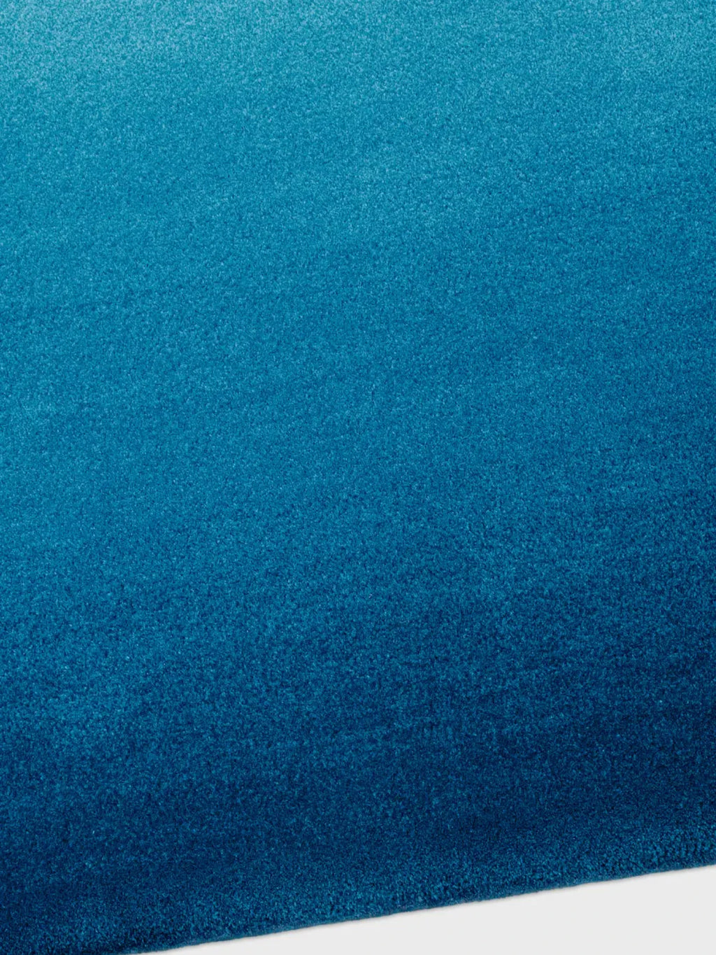 alp_ Degradé Double Rug, a contemporary area rug showcasing a dynamic gradient color palette that flows from a vibrant teal blue to a rich, deep blue.