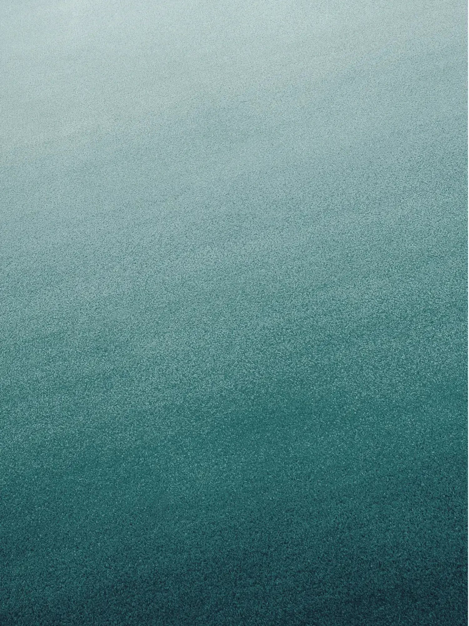 alp_ Degradé Double Rug, a contemporary gradient area rug featuring a smooth degradé ombre transition from light aqua blue to deep teal. It has a soft, plush textured pile, evoking a sense of depth and tranquility. This modern minimalist rug is perfect for adding a serene touch to a contemporary living room, a tranquil bedroom, or a stylish home office, creating a calming focal point.
