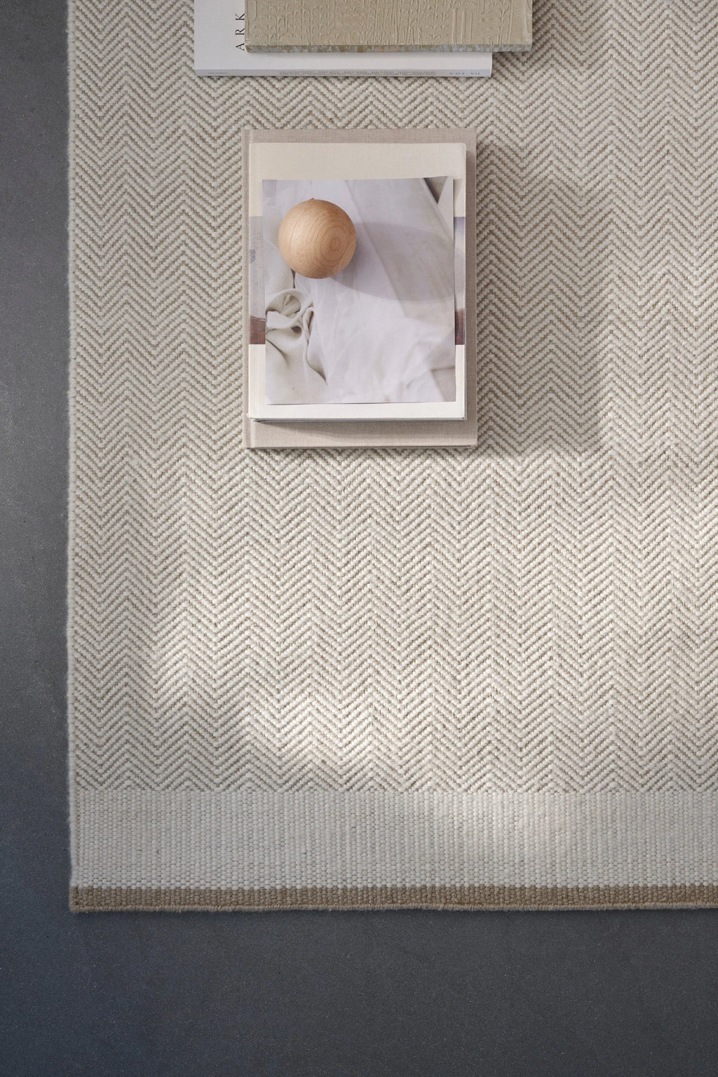 Linie Design Stratum Echo Wool Rug, a premium hand-woven wool area rug showcasing a refined cream and light beige chevron pattern, complemented by a solid flatweave border in a natural, warm tone. This textured, Scandinavian-inspired rug provides a soft underfoot feel, ideal for minimalist living rooms, organic modern bedrooms, or Japandi-style spaces.