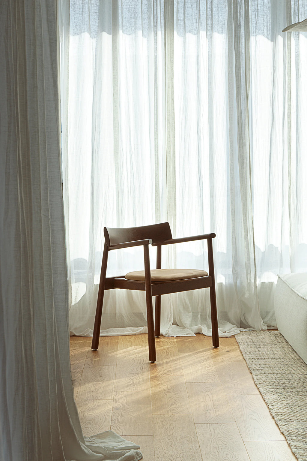 TAMO Elipsa Chair, a premium dark brown solid wood chair with a curved backrest and light brown upholstered seat, showcased on a light hardwood floor. Ideal for contemporary living spaces.