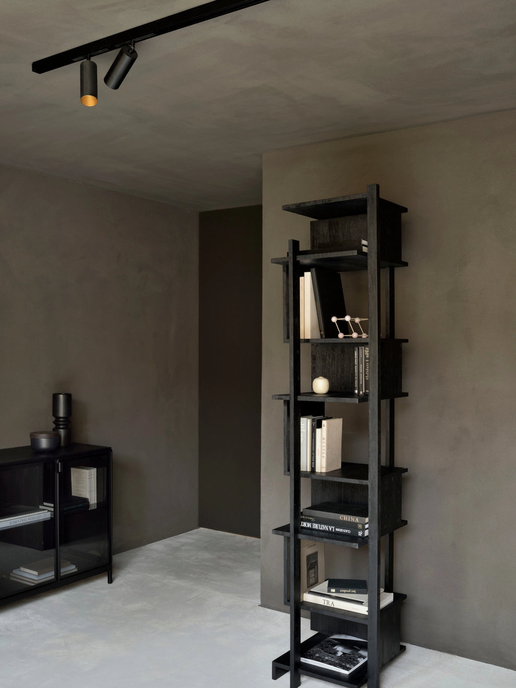 Ethnicraft Abstract Column, a tall, elegant dark teak and black bookshelf with an artistic, staggered shelf arrangement, providing ample storage and display space in a modern room.
